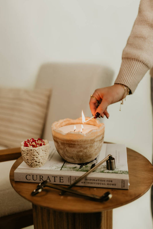 Woman lighting beautiful unique hand crafted stone candle styled on books on a wood table