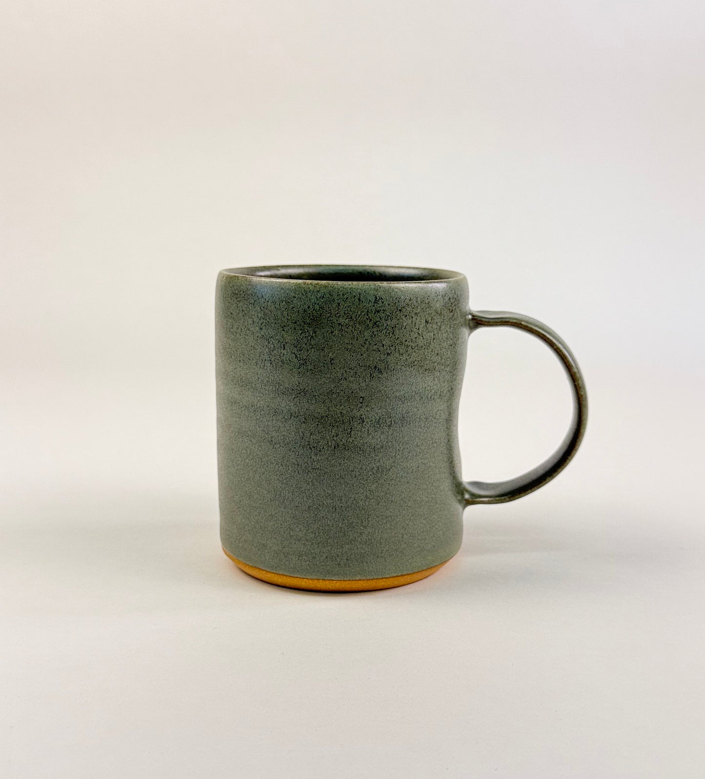 minimalist product photo of a handmade sage green ceramic mug on a white background.