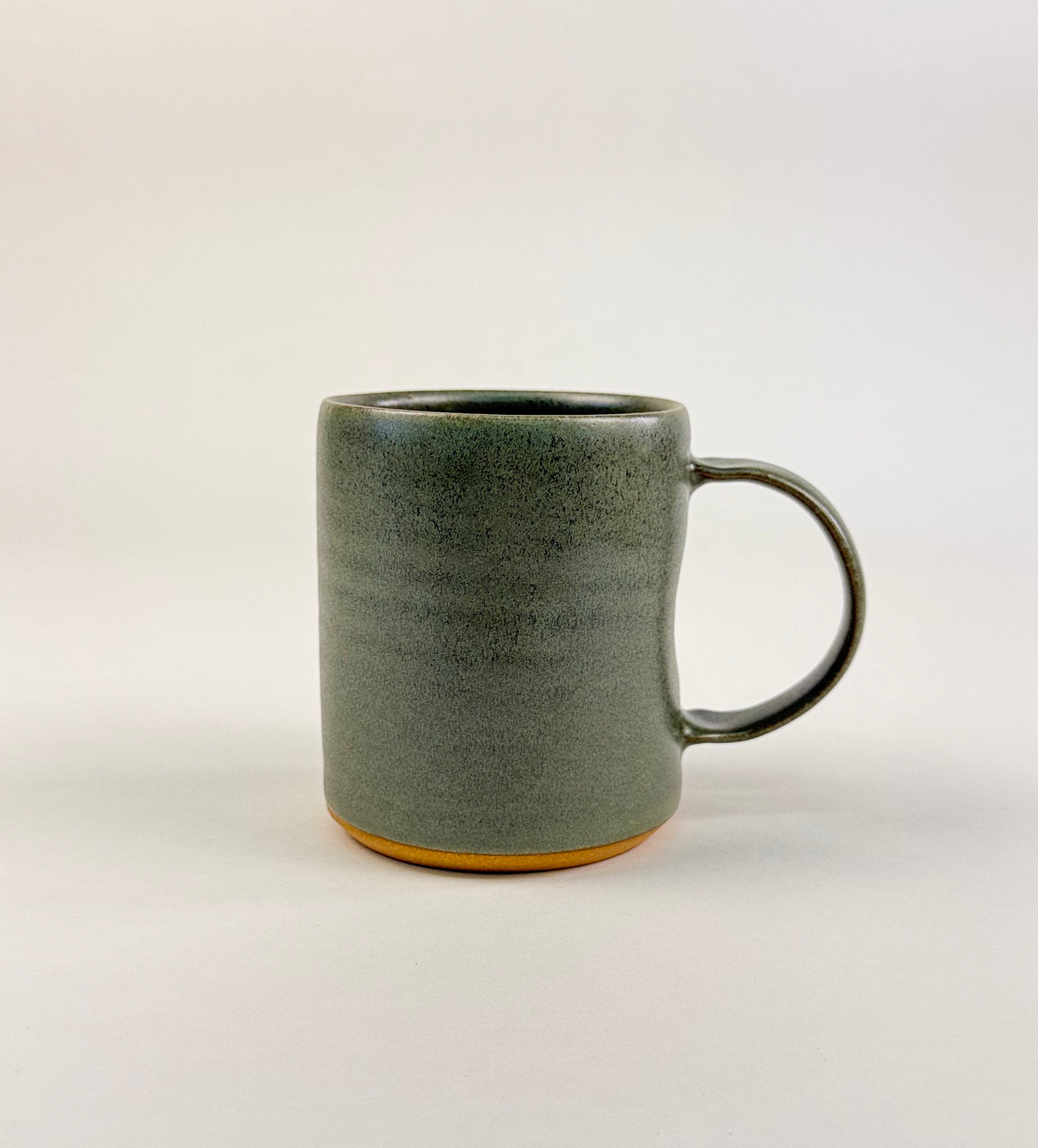 minimalist product photo of a handmade sage green ceramic mug on a white background.